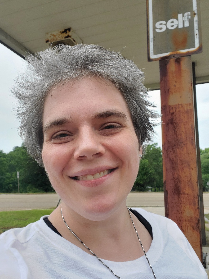 Laurie posing in front of a "Self" sign at a defunct gas station.